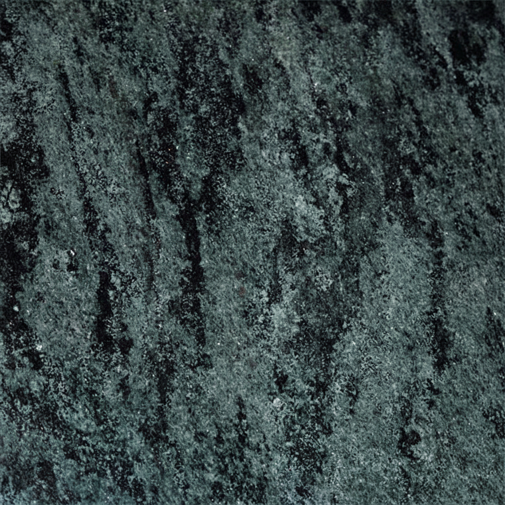 A close-up image of a dark green and black granite texture, showcasing its natural, mottled pattern and rough surface. Irregular streaks of black contrast with the deep green, accented by tiny lighter specks, emphasizing the stone's organic beauty suitable for memorials.