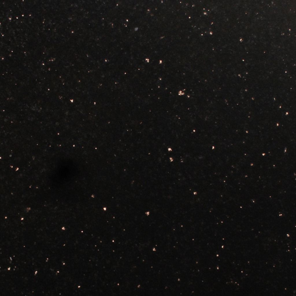 A detailed close-up of a black granite surface, showcasing its inherent sparkling flecks against a deep, dark background. This natural stone texture is often chosen for its elegant and enduring visual appeal on memorials and headstones.