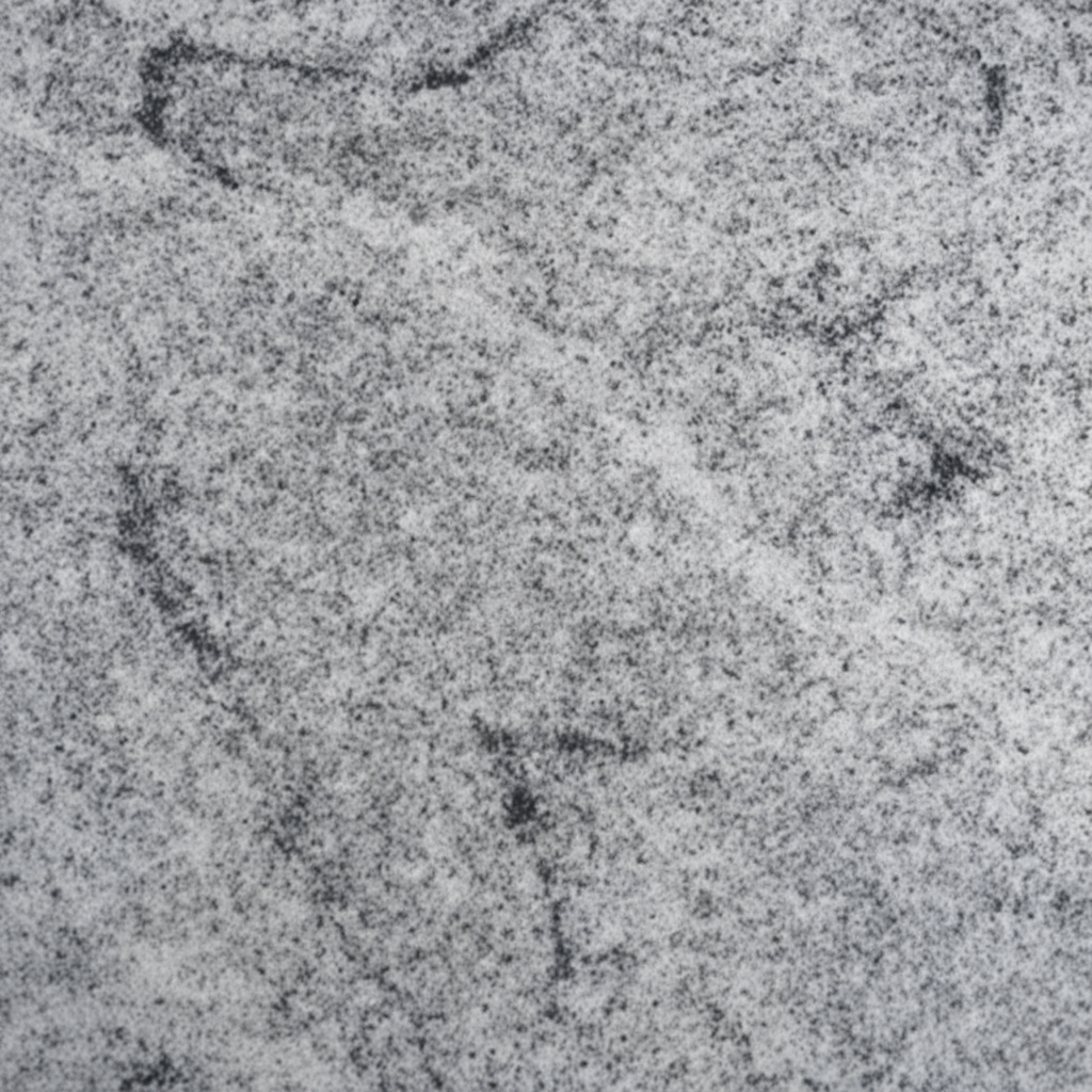 A close-up image showing the natural speckled texture of light grey granite stone, commonly used for headstones and memorials. It features a mix of white, grey, and black flecks, illustrating the durable and rustic surface of the material.